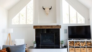 A spacious living room with a fireplace, a mounted bull skull, a large TV, and a wooden TV stand. - 🏔Views for Days! Welcome to the Missoula Lookout! 🏔  (Missoula)