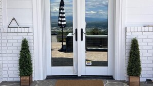 A double glass door with a "HELLO" mat in front, flanked by two potted plants, leading to a stone-paved entrance. - 🏔Views for Days! Welcome to the Missoula Lookout! 🏔  (Missoula)