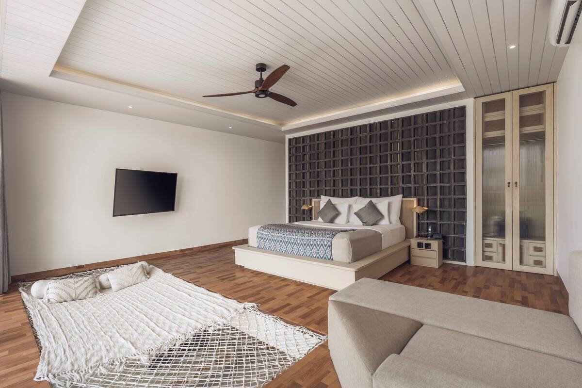 Ein modernes Schlafzimmer mit Bett, Deckenventilator, Fernseher und Kleiderschrank.