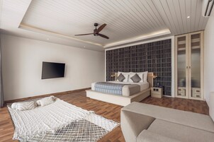 Ein modernes Schlafzimmer mit Bett, Deckenventilator, Fernseher und Kleiderschrank.