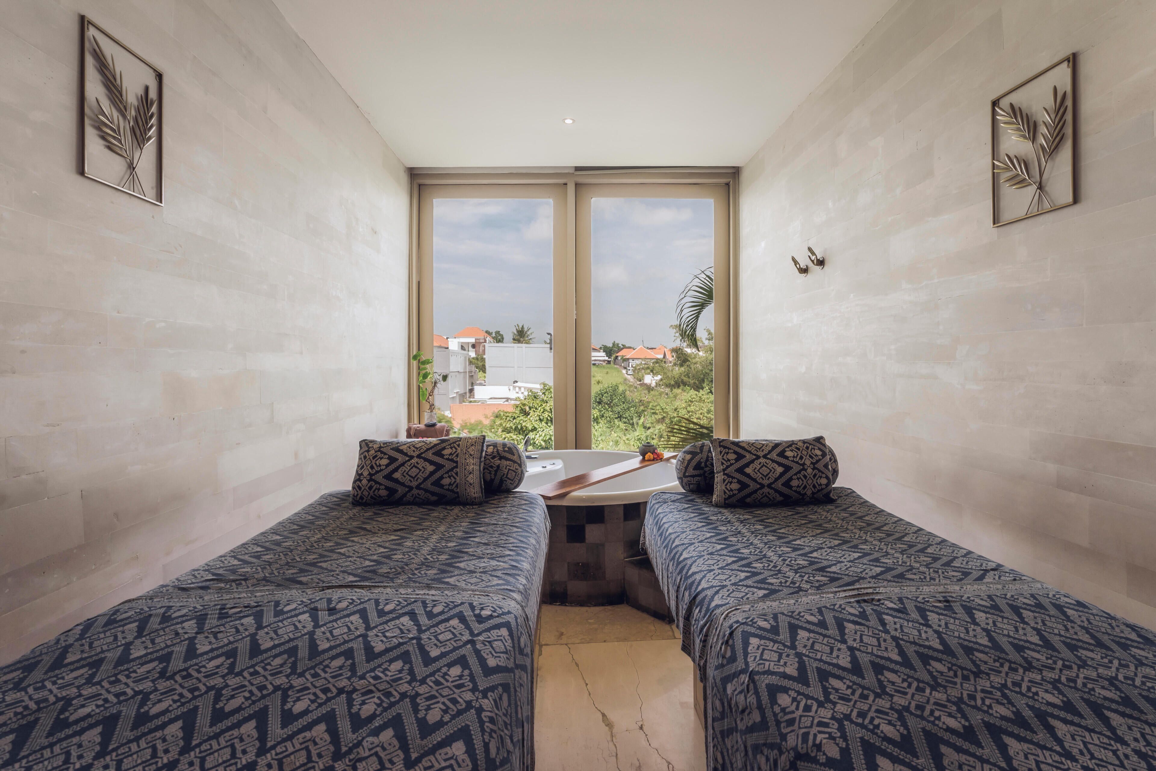 Habitación con dos camas, una mesita y vistas a edificios y zonas verdes.