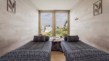 Habitación con dos camas, una mesita y vistas a edificios y zonas verdes.