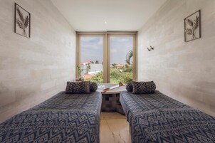 Habitación con dos camas, una mesita y vistas a edificios y zonas verdes.