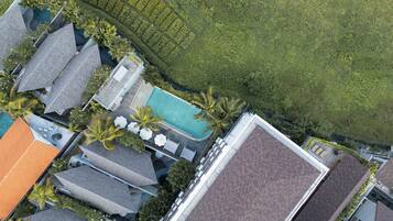 An aerial view of a residential area with multiple houses, a swimming pool, and lush greenery.