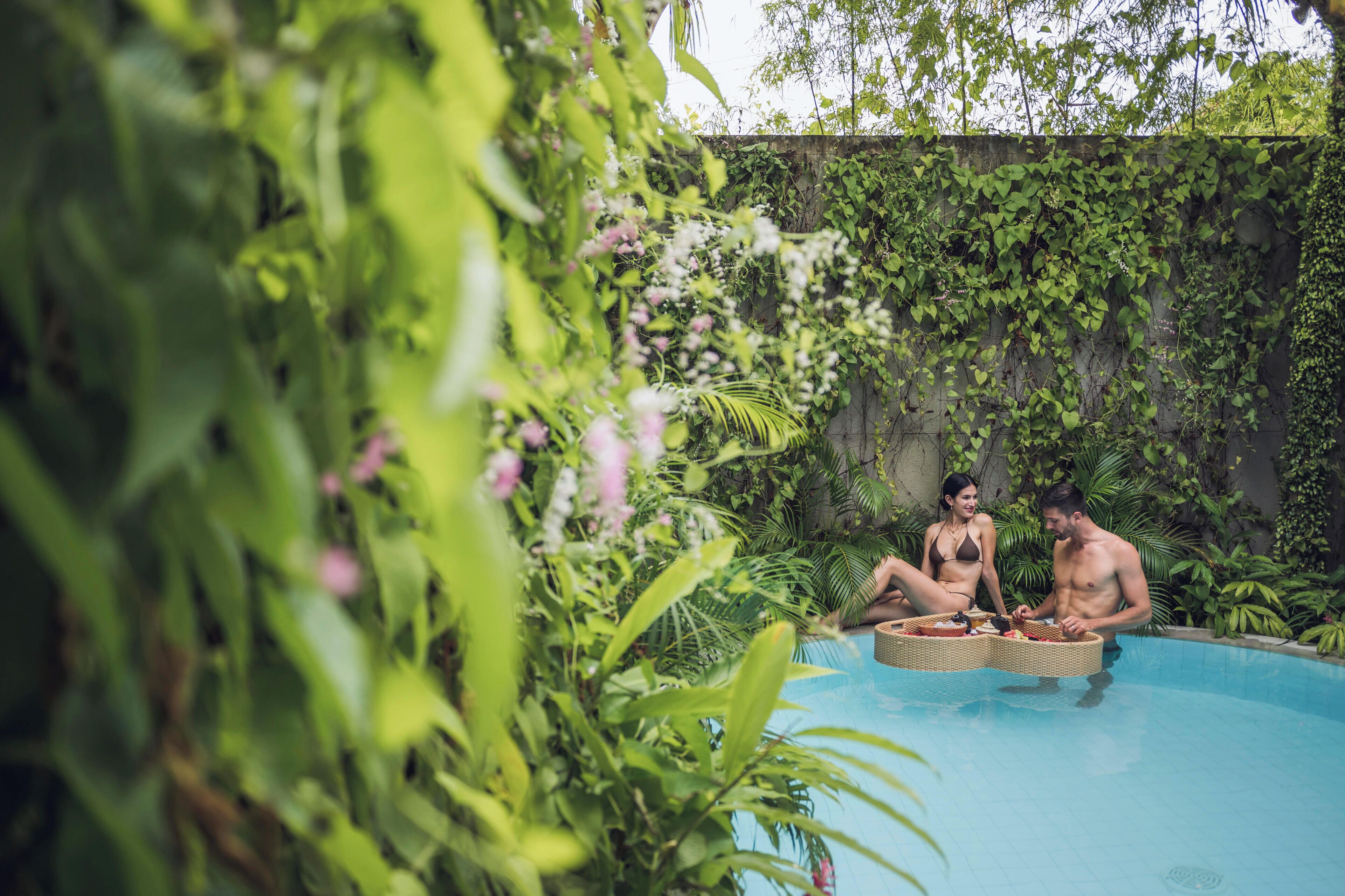 A pool area with lush greenery and a stone wall.