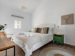 A bedroom with a bed, bedside tables, a lamp, a plant, and a window.