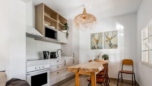 A modern kitchen with white cabinets, a wooden dining table, and a hanging light fixture. - Quinta de Santa Emilia 1 by Interhome (Alcácer do Sal)