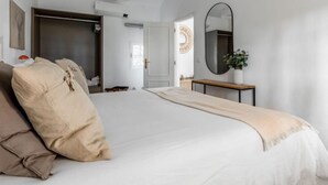 A bedroom with a large bed, a bedside table with a mirror, a wardrobe, and a door leading to another room. - Quinta de Santa Emilia 1 by Interhome (Alcácer do Sal)