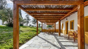 A covered outdoor patio with stone flooring and wooden beams, featuring a table and chairs. - Quinta de Santa Emilia 1 by Interhome (Alcácer do Sal)