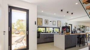 A modern kitchen with a large island, dark cabinetry, and a sliding glass door leading to a patio. - Altalune by Interhome (Novigrad (Istra))
