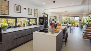 A modern kitchen with a central island, built-in appliances, and a dining area with a staircase leading to an upper level. - Altalune by Interhome (Novigrad (Istra))