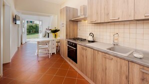 A modern kitchen with wooden cabinets, a gas stove, and a large window.