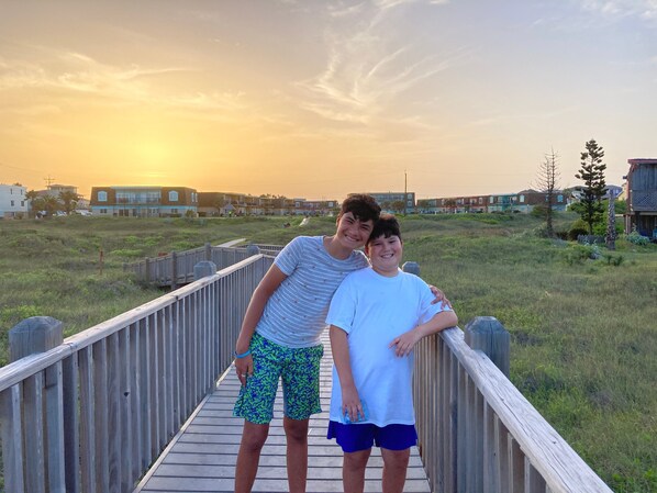 A wooden boardwalk with a sunset in the background.