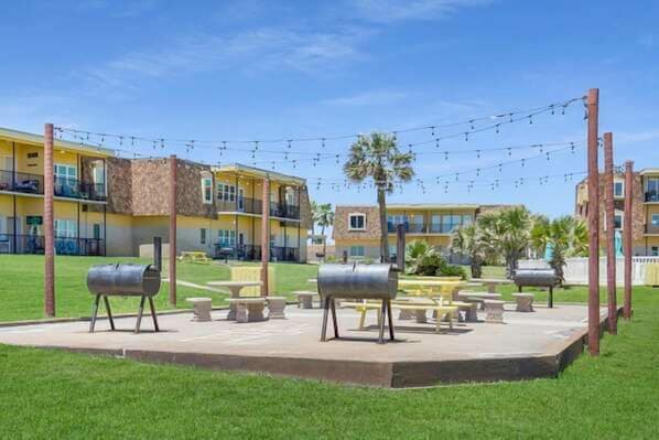 Un patio con mesas al aire libre, una parrilla y luces colgantes.