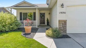 Une maison de plain-pied avec un porche à l’avant, un garage et une pelouse bien entretenue.