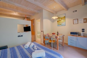 Ein Hotelzimmer mit einem Bett, einem Schreibtisch, einem Essbereich und einem Fernseher.