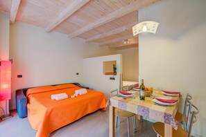 A hotel room with a bed, a dining table set with plates and glasses, and a ceiling with wooden beams.