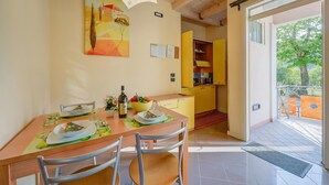 Comedor con una mesa dispuesta para cuatro, cocina con armarios amarillos y puerta corrediza de vidrio que da a un espacio exterior.