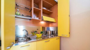 Una cocina con armarios amarillos, un lavamanos de acero inoxidable y una encimera amarilla.