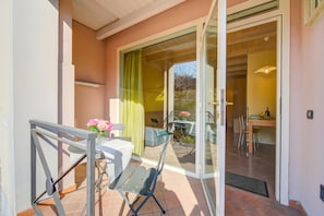 A balcony with a table, chairs, and a vase of flowers.