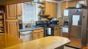 Eine Küche mit Holzschränken, einem Edelstahlkühlschrank und einer Holzinsel mit Sitzgelegenheiten.