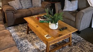 Ein Wohnzimmer mit einem großen Fisch an der Wand, einem Flachbildfernseher, zwei Sofas und einem Couchtisch mit Pflanze.