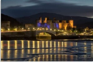 Castle situated over a serene body of water, accessible via a picturesque bridge.