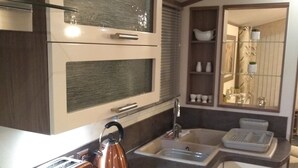 Une cuisine compacte équipée d’une cuisinière à gaz, d’une bouilloire, d’un grille-pain et d’un évier.
