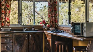 A kitchen with wooden cabinets, a sink, a stove, and a microwave. - Private garden bungalow just 200m from the beach (Fare)