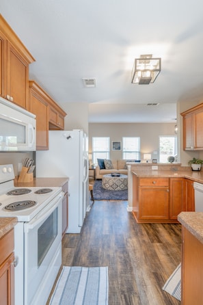 A modern kitchen with wooden cabinets, a white stove, and a refrigerator.