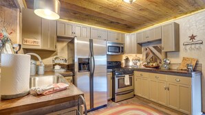Une cuisine avec un plafond en bois, des appareils en acier inoxydable et des armoires de couleur beige.