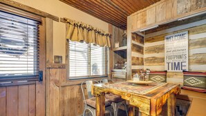 Un intérieur rustique en bois, avec une table à manger, des chaises et une pancarte indiquant « Bienvenue ».