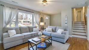 Ein Wohnzimmer mit zwei grauen Sofas, einem Holztisch und Blick ins Freie.