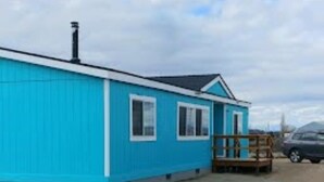 A blue building with a wooden deck and a car parked nearby.