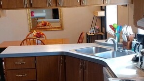 A kitchen with wooden cabinets, a stove, a sink, and a dining area with chairs and a table.