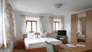 A bedroom with a wooden bed, a desk, a chair, a television, and a mirror.