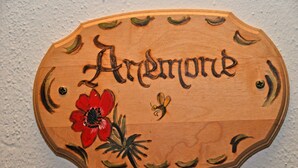 A wooden plaque with the name "Arremore" and decorative elements including a red flower and a bee.