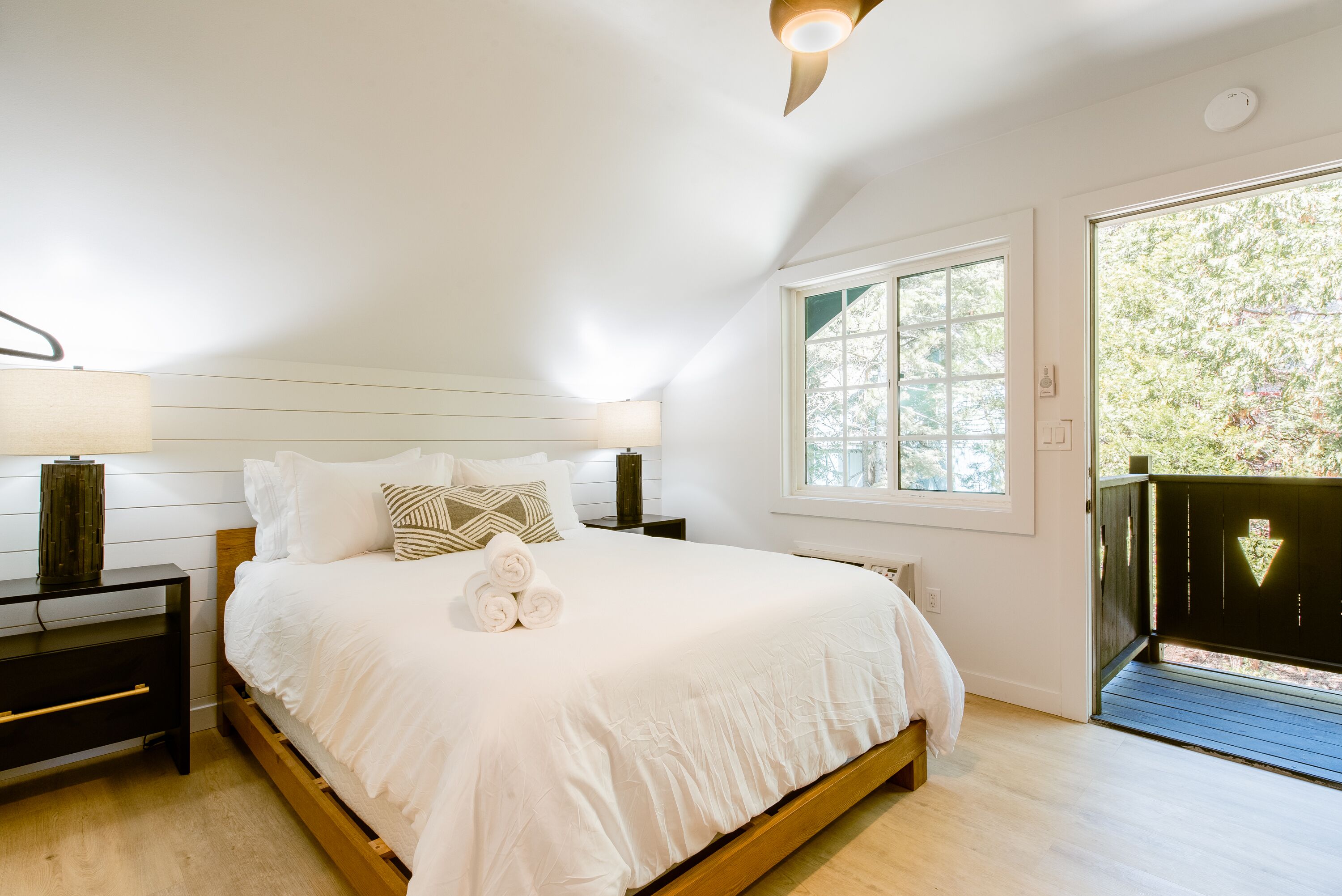 A bedroom with a bed, bedside tables, a lamp, a window, and a door.