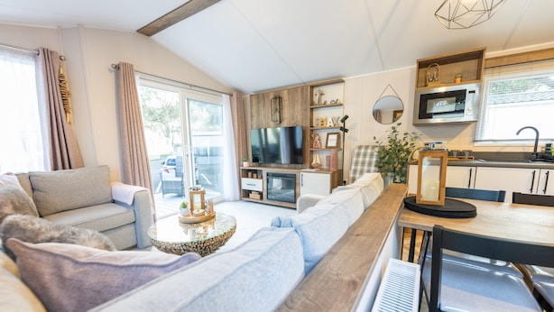 Een moderne woonkamer met een bank, een salontafel, een piano en een keukenhoek met een magnetron en een televisie.