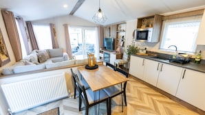 Een moderne keuken met een eettafel, stoelen, een televisie en een magnetron.