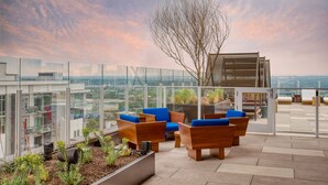 A rooftop terrace with wooden furniture and a view of the cityscape.