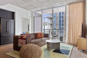 Relax in this stylish living room with a sofa, ottoman, and TV, offering a view of the city.