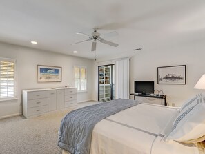 A bedroom with a bed, a ceiling fan, a TV, and a closet. - Family Getaway Beachside, Heated Pool Access (Tybee Island)