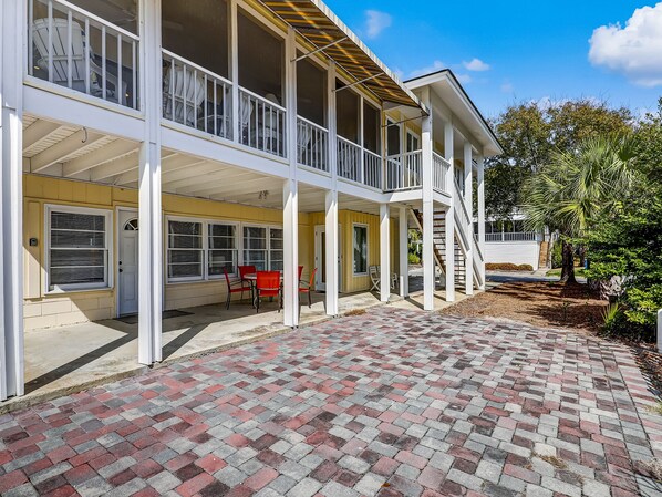 A two-story building with a covered patio area, multiple windows, and a brick pathway. - Family Getaway Beachside, Heated Pool Access (Tybee Island)