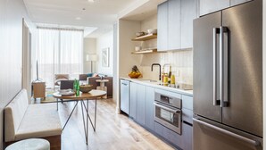 Une cuisine moderne dotée d’appareils électroménagers en acier inoxydable, de meubles en bois et d’un coin repas avec une table et des chaises.