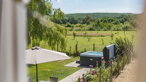 Eine Terrassenanlage mit Whirlpool, Gartenmöbeln und Blick auf eine üppige grüne Landschaft.