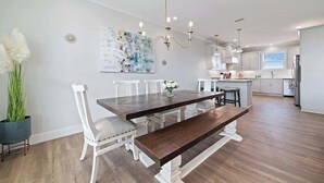 Una cocina moderna con armarios blancos, una mesa de comedor de madera y una araña.