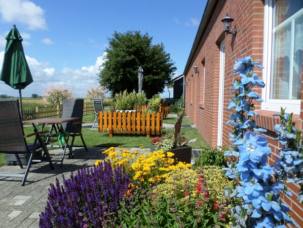 En terrasse med havemøbler, en murstensbygning og et udvalg af blomster.