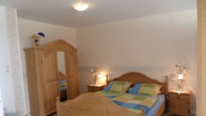 Een slaapkamer met een houten bed, twee nachtkastjes met lampen, een kledingkast en een stoel.