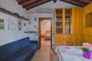 A cozy room with a blue sofa, wooden cabinets, and a dining table with a floral tablecloth.